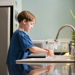 boy in blue crew neck t-shirt standing beside white wooden door